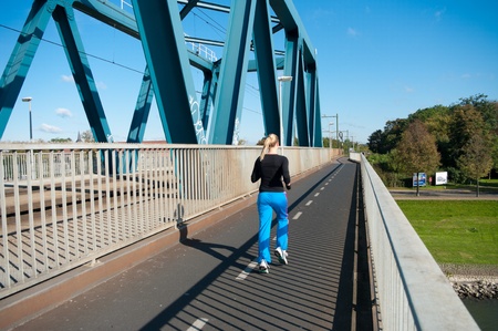 young woman jogging over a railway bridgeの写真素材