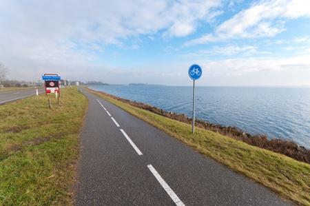 empty bicycle path with a road sign along a lakeの写真素材