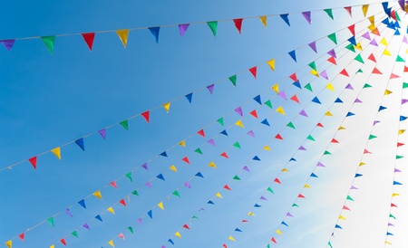 bunting flags blowing in the wind against a saturated blue skyの写真素材