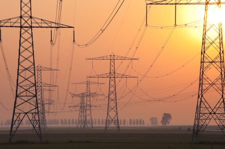 silhouette of electricity pylons in orange sunriseの写真素材