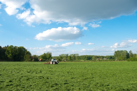 farmer busy with tractor to flip just mowed grassの写真素材