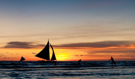 tropical beach with sailing boats at sunsetの写真素材