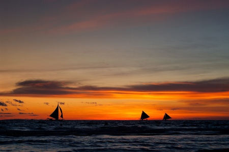 tropical beach with sailing boats at sunsetの写真素材