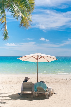 woman relaxing under a white parasol on a tropical beachの写真素材