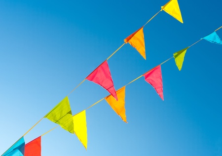 colorful bunting flags against a blue saturated skyの写真素材