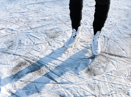 woman standing on white skates on a snowy ice floorの写真素材