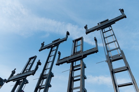 several forklifts for containers against a blue sky