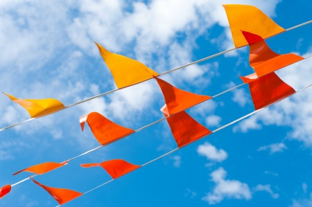 red and orange bunting flags against a blue skyの写真素材