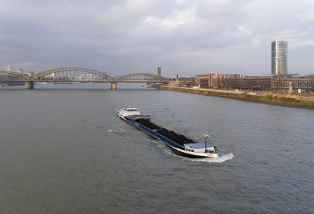 freighter loaded with coal on Rhine river at Cologne, Germany. In the background the famous Hohenzollern bridgeの写真素材