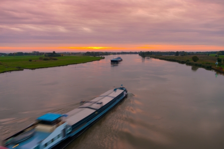 cargo ships on the IJssel river at dawn in the Netherlandsの写真素材
