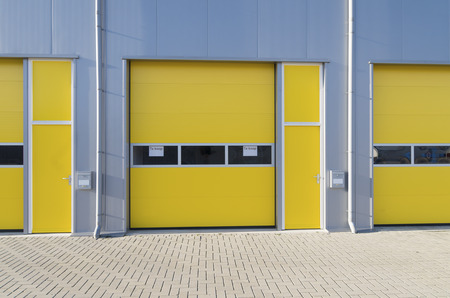 exterior of a commercial warehouse with yellow roller doorsの写真素材