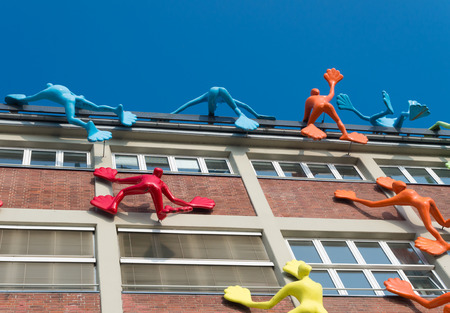 colorful figures on an office building in dusseldorf, germany. This office building is emphasized by 28 giant plastic figures, known locally as Flossies, 'climbing' the dockside of the officeのeditorial素材