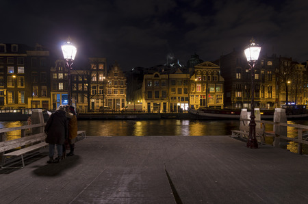 amsterdam canal at night with some tourists in frontのeditorial素材