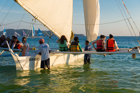 BORACAY, PHILIPPINES - MAY 17, 2015: Unknown tourists heading for a sunset sailing trip on a...