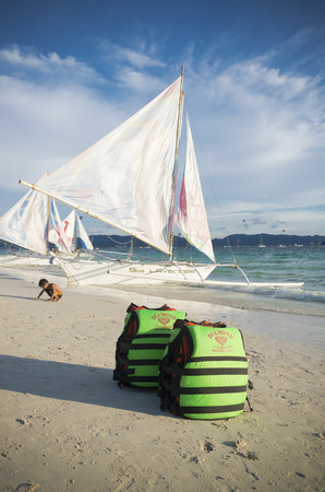 BORACAY, PHILIPPINES - MAY 20, 2015: Green life jackets on a tropical beach with some sailing boats in the backgroundの写真素材