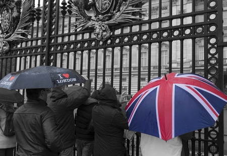 LONDON, ENGLAND - OCTOBER 21: Tourists looking through a gate of Buckingham palace on a rainy day. Buckingham palace is the official residence of Queen Elizabeth IIのeditorial素材