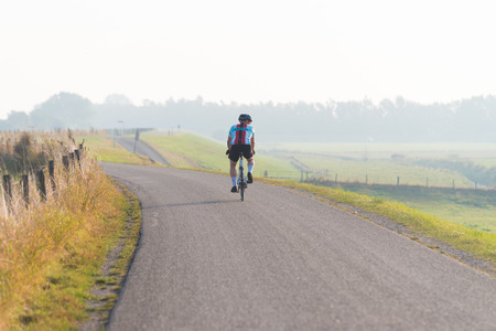 MAURIK, NETHERLANDS - SEPTEMBER 24, 2016: Unknown cyclist on a dike on an early autumn morningのeditorial素材