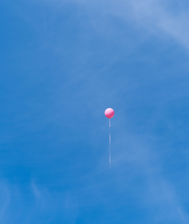 single pink balloon high in the skyの写真素材