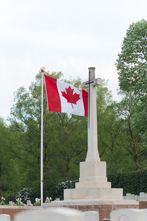 HOLTEN, NETHERLANDS - APRIL 29, 2018: Canadian flag next to a remembrance cross on the Holten canadian war cemetaryのeditorial素材