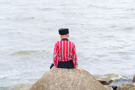 Unknown boy at the sea in traditional costume on the Urkerdays. Urk is on of the best-known fishing villages in the country with the largest fishing fleet.の写真素材