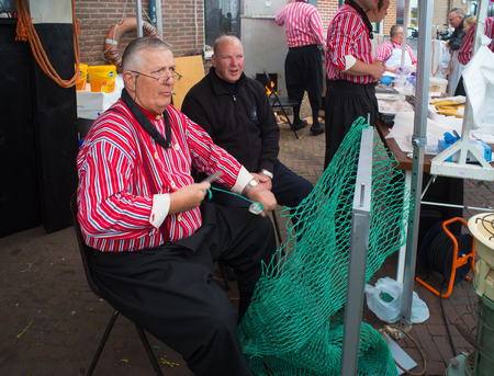 URK, NETHERLANDS - MAY 19, 2018: Unknown man in traditional clothes making fishing nets on the Urkerdays. Urk is on of the best-known fishing villages in the country with the largest fishing fleet.のeditorial素材