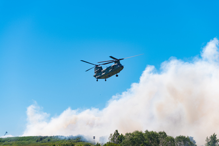 HENGELO, NETHERLANDS - JULY 1, 2018: Dutch Chinook army helicopter extinguishes a large fire at a local waste processing company during a hot summerのeditorial素材