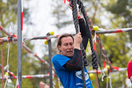 OLDENZAAL, NETHERLANDS - MAY 7, 2017: Unknown athlete hanging on a rope during a survival run