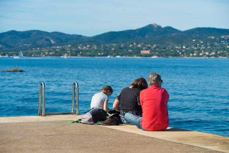 ST TROPEZ, FRANCE - OCTOBER 24, 2017: Unknown family relaxing on pier in the St. Tropez bayのeditorial素材