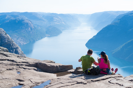 PULPIT ROCK, NORWAY - JULY 26, 2018: Unknown couple enjoying the stunning view on Pulpit Rock. The Pulpit Rock or Preacherâs Chair is a tourist attraction in the municipality of Forsand in Rogaland countyのeditorial素材