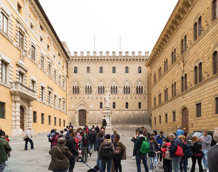 SIENA, ITALY - APRIL 22, 2019: Tourists on one of the many squares in the italian city with the statue of sallustio bandini in the backgroundのeditorial素材