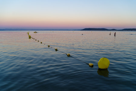 yellow buoys floating on a lake at sunsetの写真素材