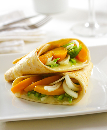 Two healthy vegetarian tortilla wraps on a plate with blurred background.の写真素材