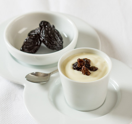 A yogurt cream custard dessert with prunes and raisins in a bowlの写真素材