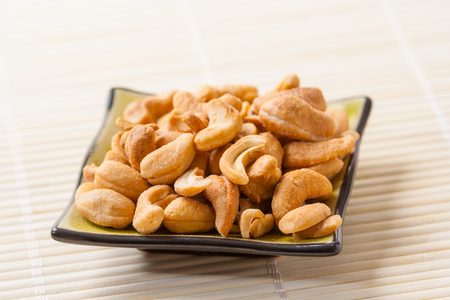 Closeup of a small plate with toasted salted cashew nuts.の写真素材