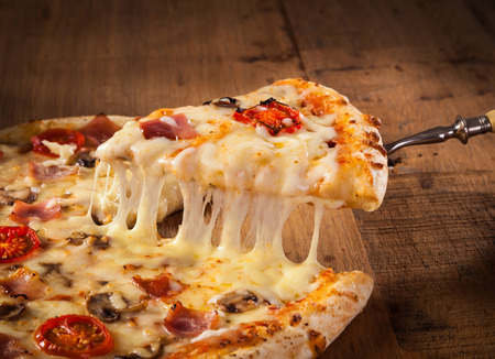 A slice of hot pizza just from the oven with melted cheese drippingの写真素材