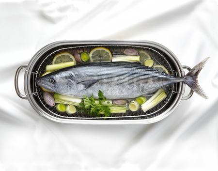 Fresh raw tuna fish in a cooking pot with vegetables.
