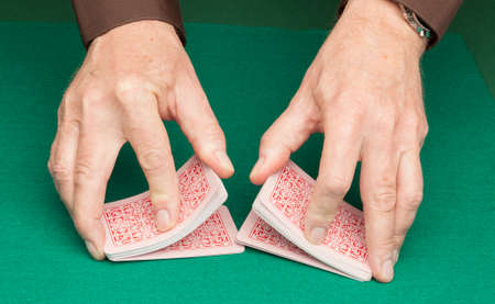 Hans shuffling playing cards on a green felt mat.