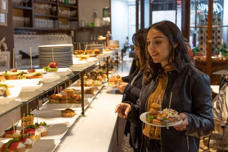BARCELONA, SPAIN - NOVEMBER 23, 2019: Tourists enjoy the typical tapas food at the Barcelona restaurants.のeditorial素材