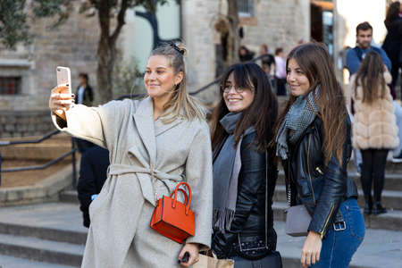 BARCELONA, SPAIN - NOVEMBER 23, 2019: Three young women take selfies in front of the Barcelona cathedral as part of a shopping weekend.のeditorial素材