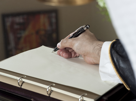 Saudi Arabian Man Hand Writing on A Notebook in a Luxury Home Environment, wearing Saudi Thob, Ghutra and Black Bishtの写真素材