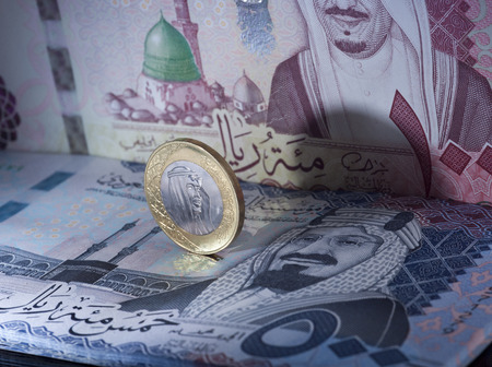 Saudi Riyal Coin Standing on Top of Banknotes