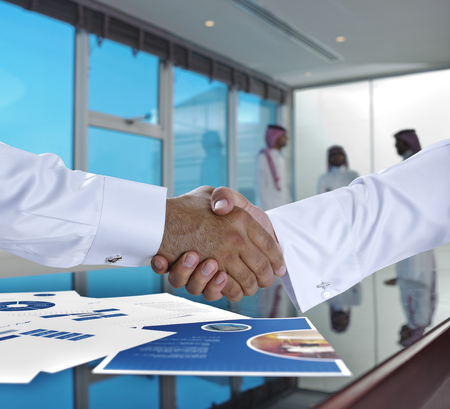 Saudi Arab businessmen shaking hands, and making agreement or a deal in a meeting roomの写真素材