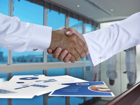 Saudi Arab businessmen shaking hands, and making agreement or a deal in a meeting roomの写真素材