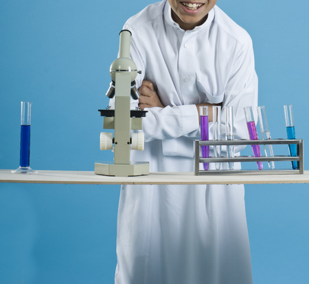 School boy using a microscope with colorful chemicals in test tubesの写真素材