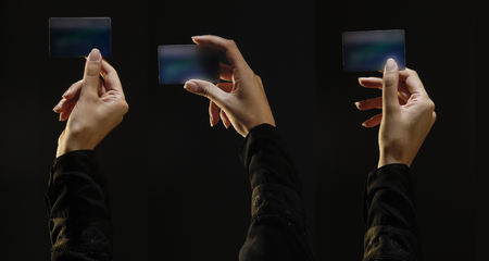 Three female hands holding credit Cards, top lit on black background