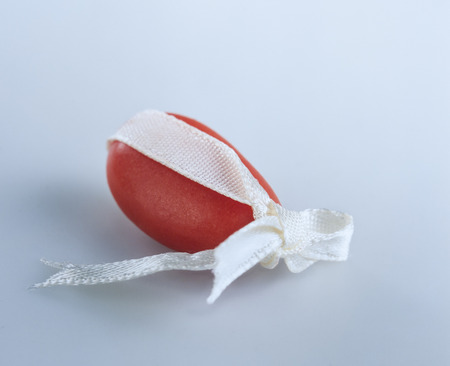 Red candy-coated almond tied with a white ribbonの写真素材