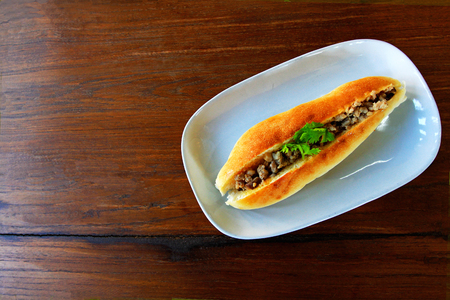 Thai bread stuffed with pork in the white plate on the brown wooden table on top viewの写真素材