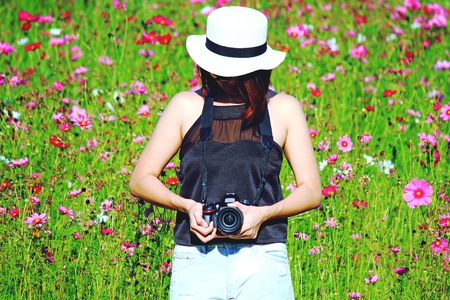 Chiangrai, Thailand - December 7, 2016: Hipster girl holding Nikon DSLR camera and standing among in cosmos flowers garden for backgroundのeditorial素材