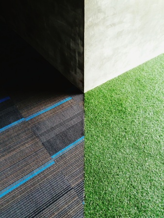 Light and shadow on the corner concrete wall with grass and gray carpetの写真素材