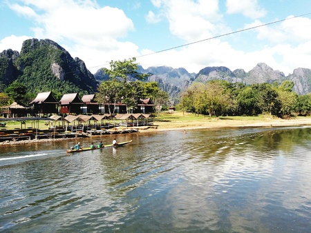 Tourist taking long tail boat and seeing mountain range view, river side and many wooden house at...